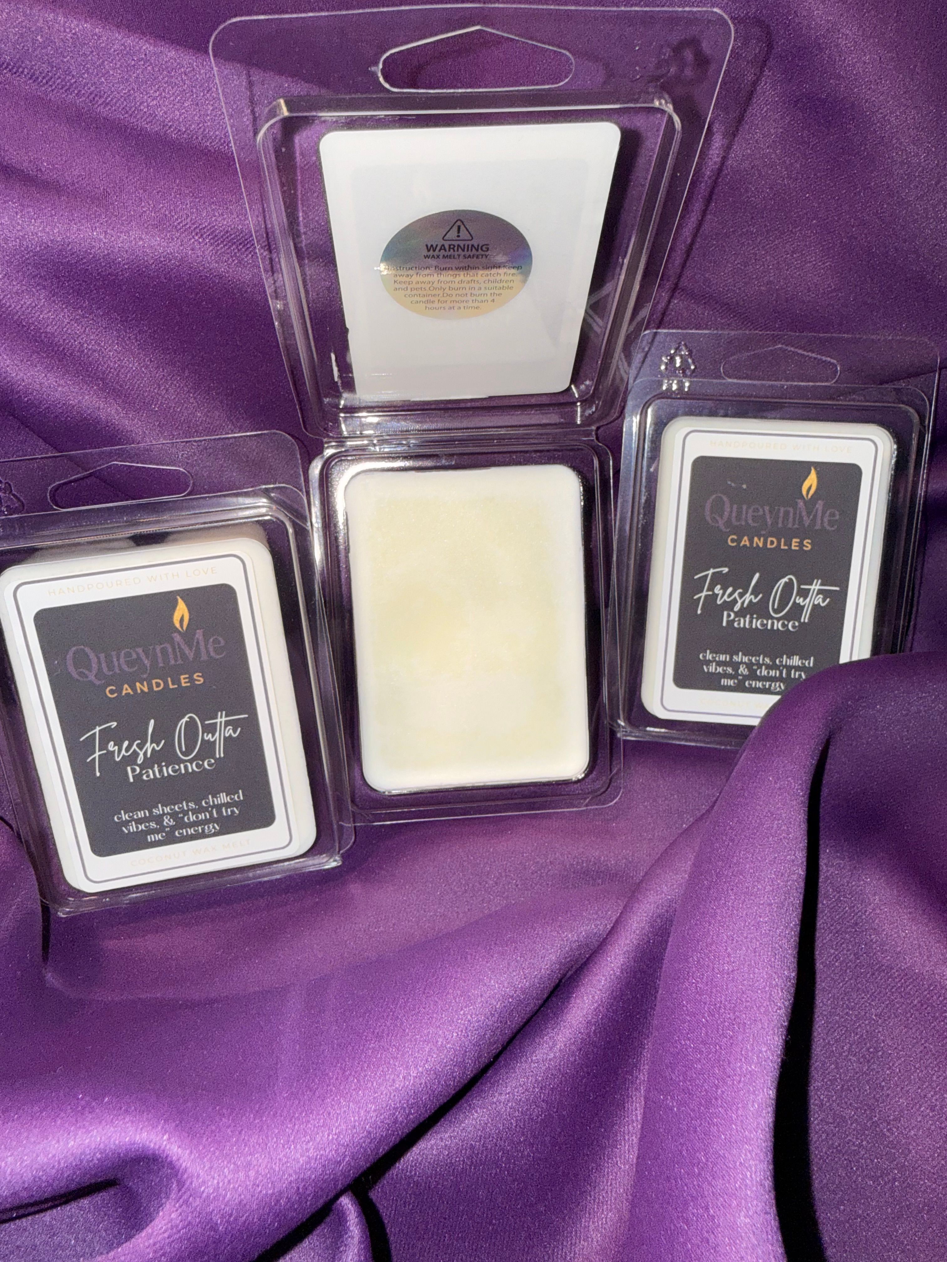 Three makeup products in clear plastic cases on purple fabric, with one open showing a white sponge or applicator.