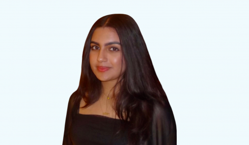 Portrait of a woman with long dark hair wearing a black top, smiling slightly, against a light background.