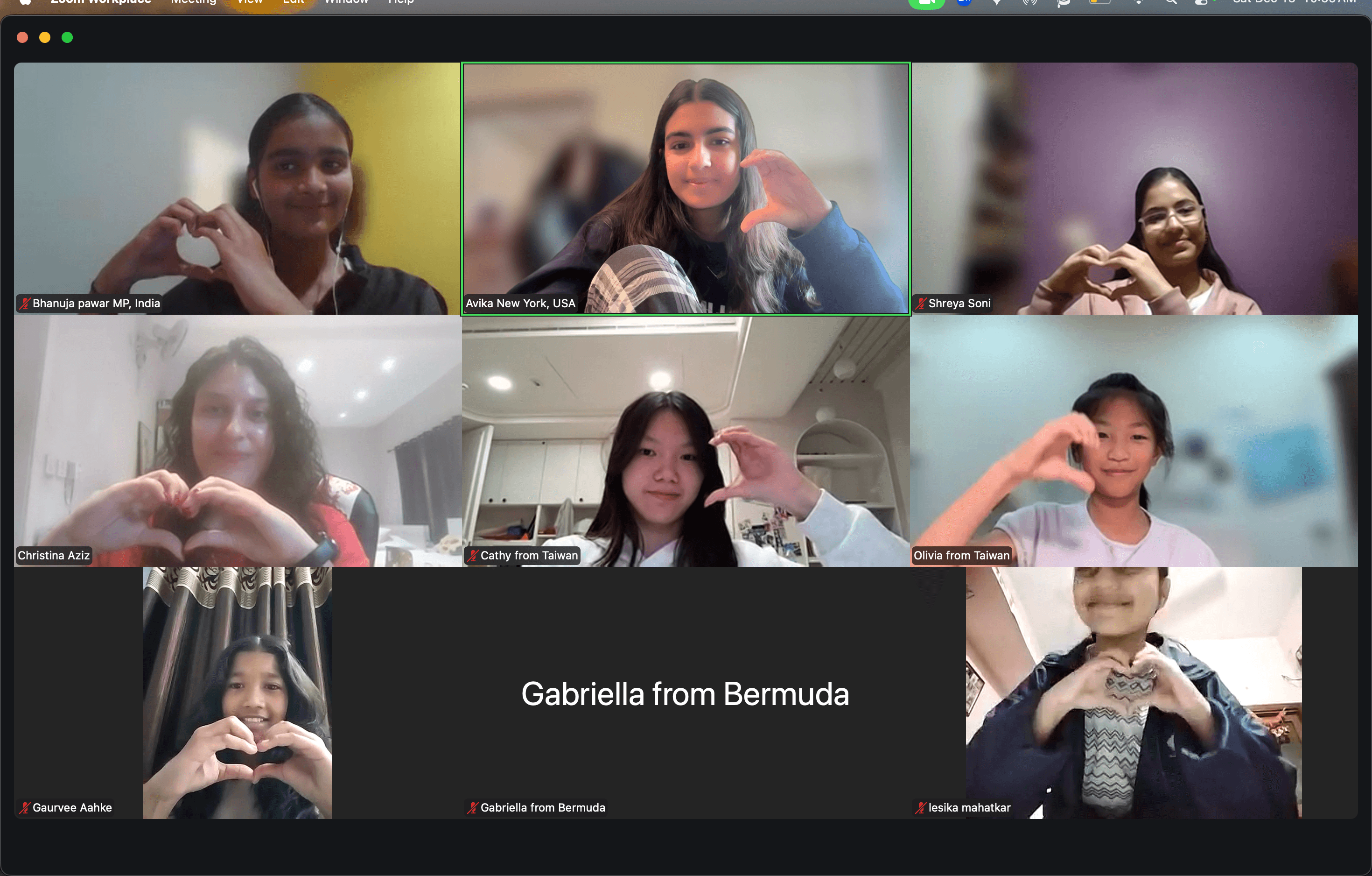 Six people on a video call, all making heart shapes with their hands, with a black screen showing a name in the center.
